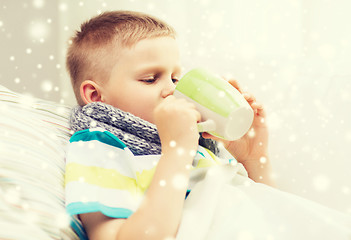 Image showing ill boy with flu in bed drinking from cup at home