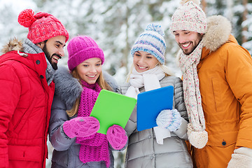 Image showing smiling friends with tablet pc in winter forest