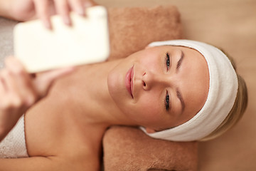 Image showing close up of smiling woman with smartphone in spa