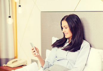 Image showing happy businesswoman with smartphone in hotel room