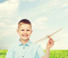 Image showing smiling little boy holding a wooden airplane model