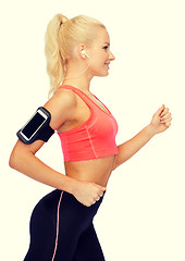 Image showing sporty woman running with smartphone and earphones