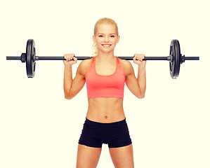 Image showing smiling sporty woman exercising with barbell