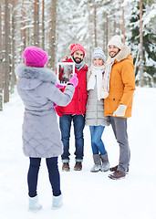 Image showing smiling friends with tablet pc in winter forest