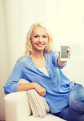 Image showing smiling woman with blank smartphone screen at home