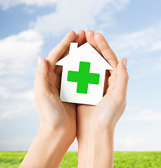 Image showing hands holding paper house with green cross