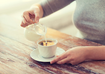 Image showing close up of female pouring milk into coffee
