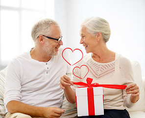 Image showing happy senior couple with gift box at home