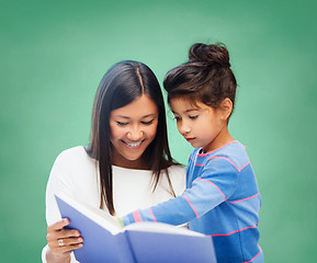 Image showing happy teacher and little schoolgirl reading book