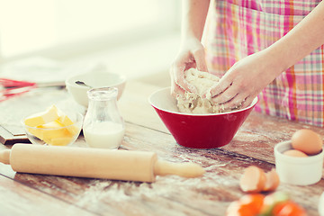 Image showing close up of female hands kneading dough at home