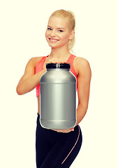 Image showing smiling sporty woman with jar of protein