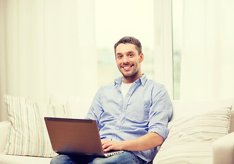 Image showing smiling man working with laptop at home