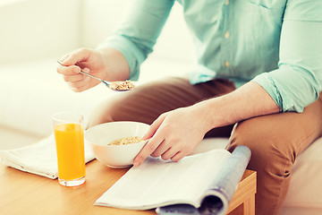 Image showing close up of man with magazine eating breakfast