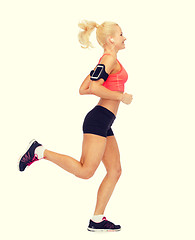 Image showing sporty woman running with smartphone and earphones