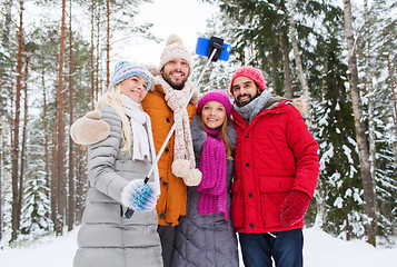 Image showing smiling friends with smartphone in winter forest