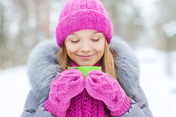 Image showing smiling young woman with cup in winter forest