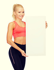 Image showing smiling sportswoman with white blank board