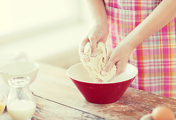 Image showing close up of female hands kneading dough at home