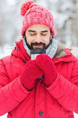 Image showing smiling young man with cup in winter forest