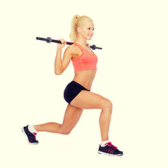 Image showing smiling sporty woman exercising with barbell