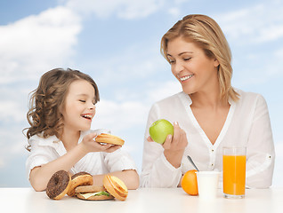 Image showing happy mother and daughter eating breakfast