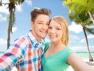 Image showing smiling couple with smartphone on summer beach