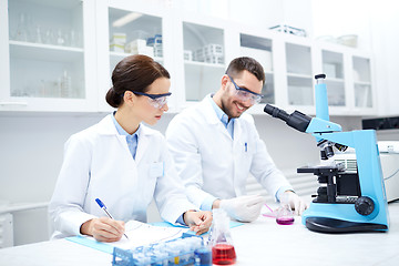 Image showing scientists with clipboard and microscope in lab