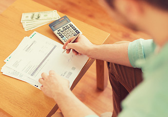 Image showing close up of man counting money and making notes