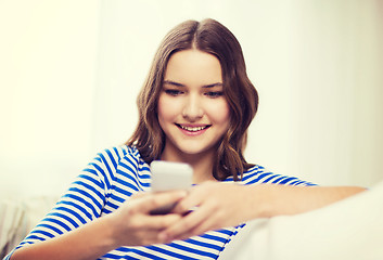 Image showing smiling teenage girl with smartphone at home