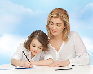 Image showing happy mother and daughter writing in notebook