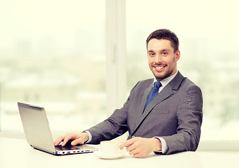 Image showing smiling businessman with laptop and coffee