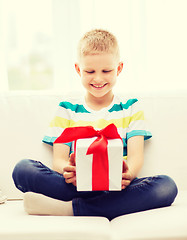 Image showing smiling little holding gift box sitting on couch