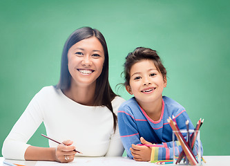 Image showing happy teacher and little schoolgirl drawing