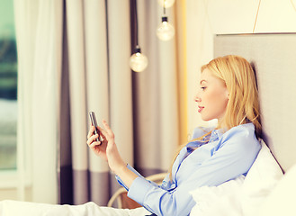 Image showing happy businesswoman with smartphone in hotel room