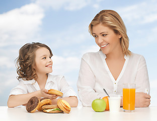 Image showing happy mother and daughter eating breakfast