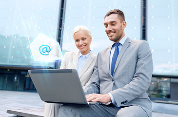 Image showing smiling businesspeople with laptop sending e-mail