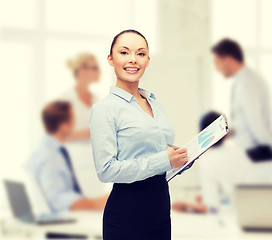 Image showing young smiling businesswoman with clipboard and pen