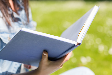 Image showing close up of young girl with book in park