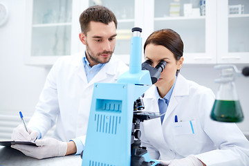 Image showing scientists with clipboard and microscope in lab