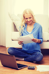 Image showing smiling woman with papers, laptop and calculator