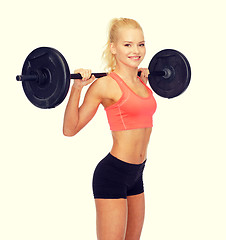 Image showing smiling sporty woman exercising with barbell