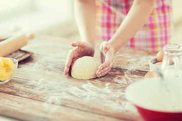 Image showing close up of female hands kneading dough at home