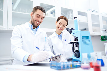 Image showing scientists with clipboard and microscope in lab