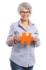 Image showing Elderly woman holding a puzzle piece