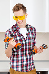 Image showing smiling repairman in yellow safety glasses selects tool