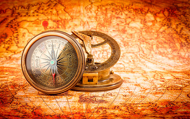 Image showing Vintage compass lies on an ancient world map.