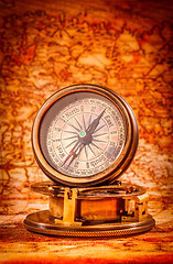 Image showing Vintage compass lies on an ancient world map.