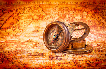 Image showing Vintage compass lies on an ancient world map.