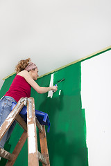 Image showing Woman paints the wall green