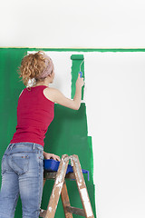 Image showing Woman on ladder painting wall green